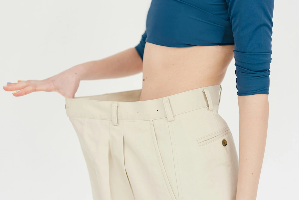 Woman displaying old pants after weight loss