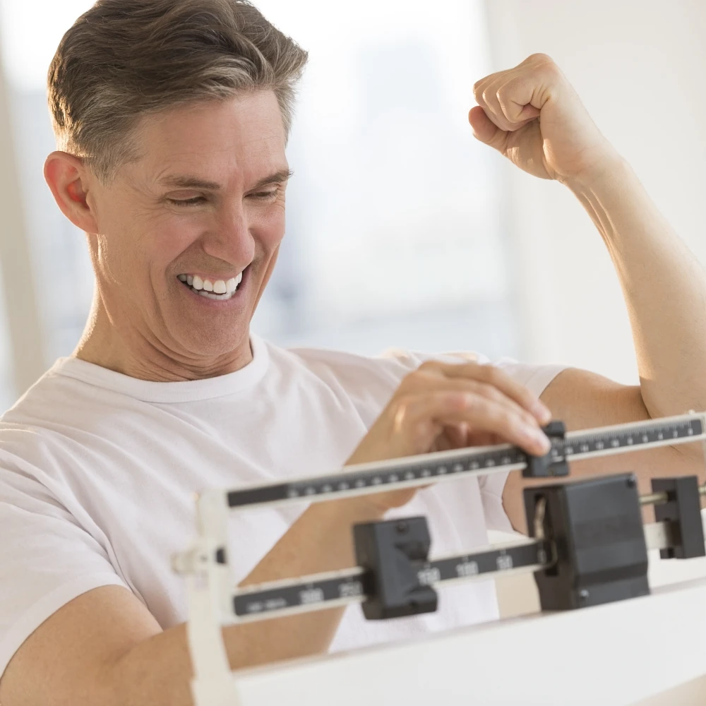 Happy man checking his weight on the scale after Semaglutide