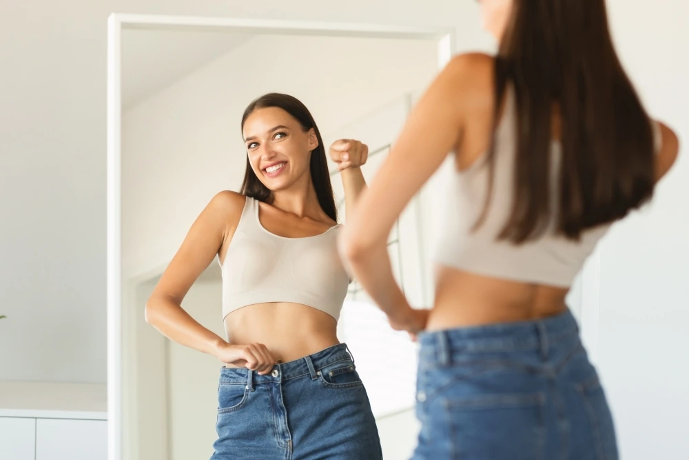 Confident woman looking in the mirror after weight loss