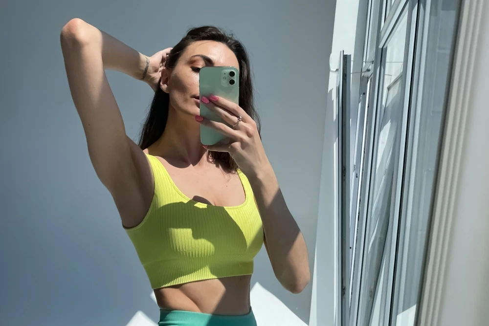 Woman taking a mirror selfie after post-weight loss plastic surgery