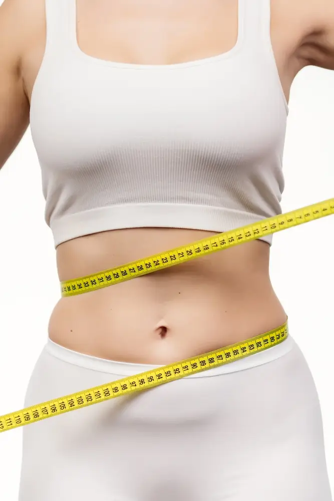 woman posing in her old pants showing her weight loss progression