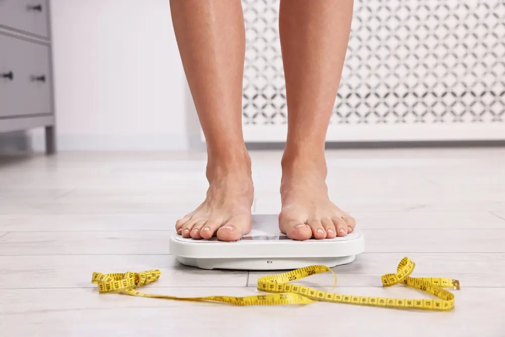 woman standing on a scale with measuring tape at feet