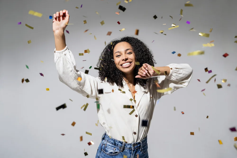 Happy 30s woman dancing with confetti falling