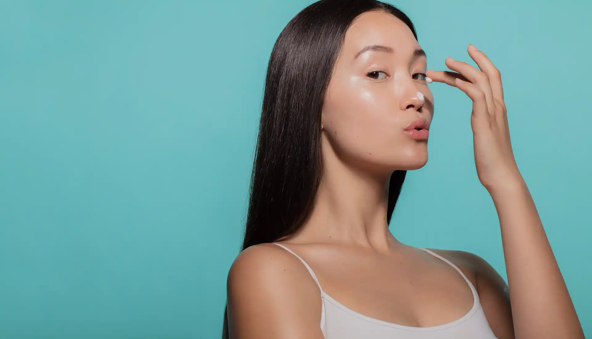 A Gen Z woman applying facial skincare as part of an early, preventative skincare routine